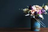Various fresh flowers arrangement in metalic vase on wooden table