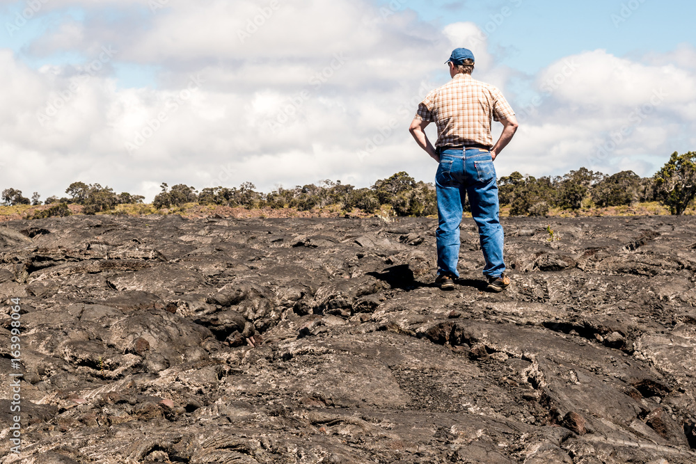 A man is standing on lava land at the Island of Hawaii