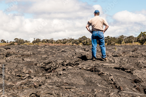 A man is standing on lava land at the Island of Hawaii © Yan