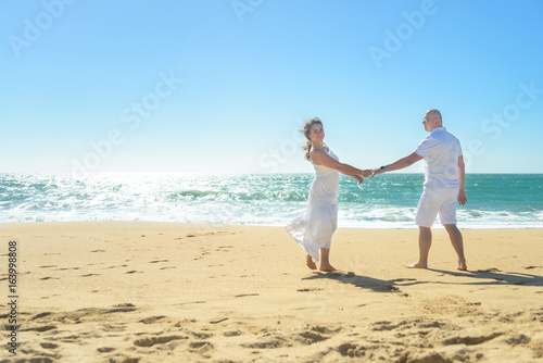 Young romantic couple walking on the beach holding hands