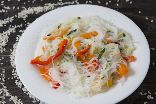 Rice noodles Funchoza with vegetables in a white plate. Traditional Korean cuisine.
