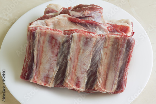 Uncooked veal ribs on a white plate. Meat halal.
