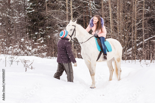 Girl, horse trainer and white horse in a winter