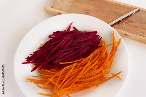 Grate carrots and beets on a white plate. Healthy food.
