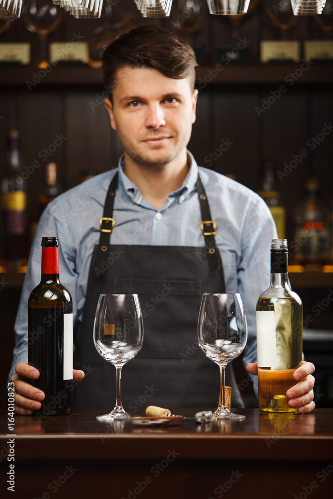 Sommelier with bottles of red and white wine and wineglasses
