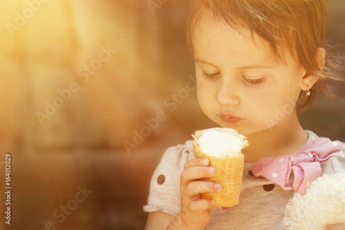 Little cute child girl eating ice cream in sunlight  food  dessert  childhood  satisfaction  carelessness 