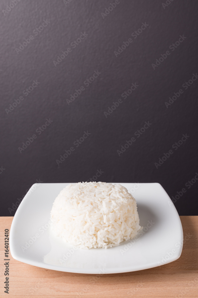 Steamed rice on white plate wood background