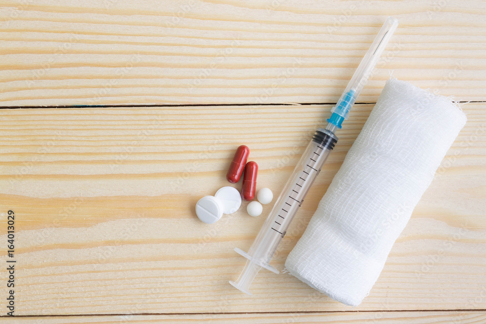 A disposable syringe and tablets on a wooden table. Health and medicine. A disposable syringe and tablets on a wooden table. Health and medicine.