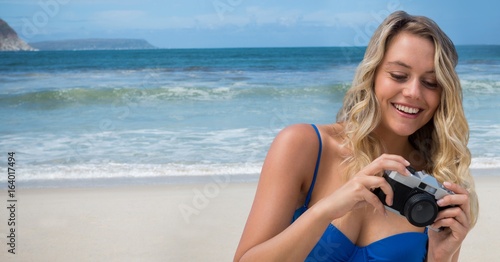 Millennial woman looking down at camera against beach