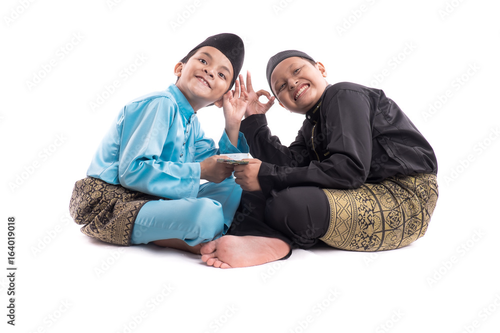 Portrait of little boys posing at studio with traditional malay clothes , showing and surprised looking at camera isolate on white background Portrait of little boys posing at studio with traditional malay clothes , showing and surprised looking at camera isolate on white background