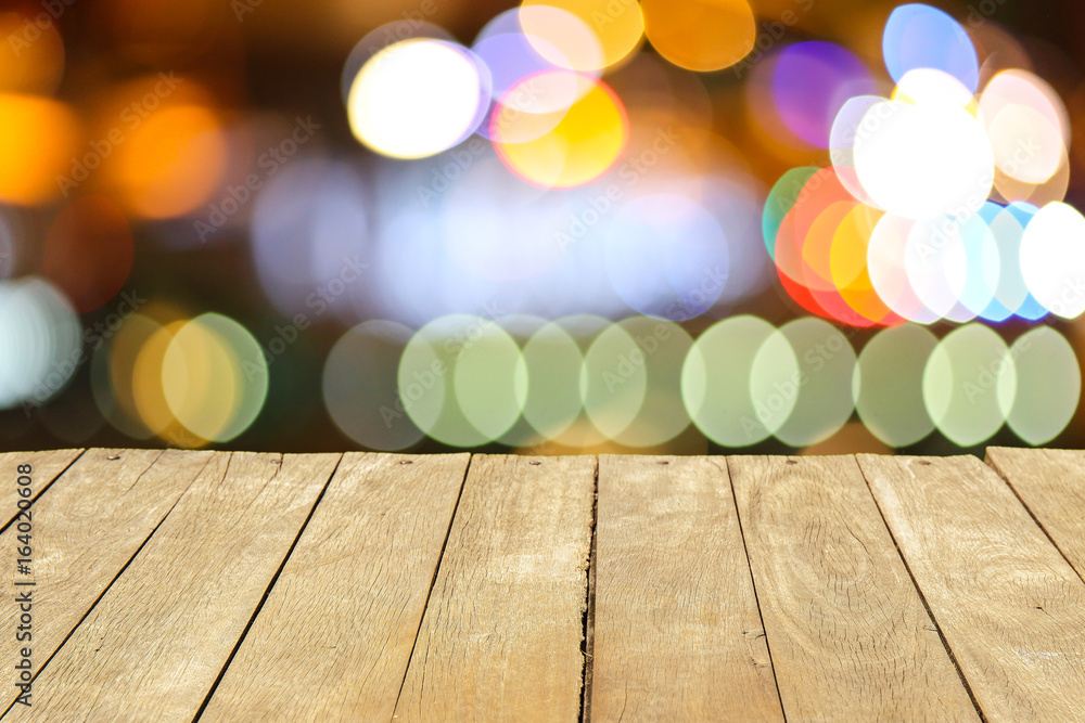 Empty old wooden table or plank with bokeh of light from road or street with city tower on background for product display. Empty old wooden table or plank with bokeh of light from road or street with city tower on background for product display.