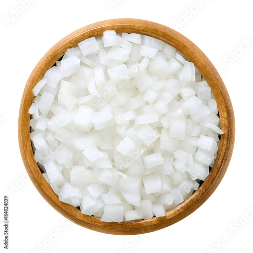 White onion cubes in wooden bowl. Chopped fresh, raw Allium cepa, also bulb or common onion. Vegetable, ingredient and staple food. Isolated macro food photo close up from above on white background.