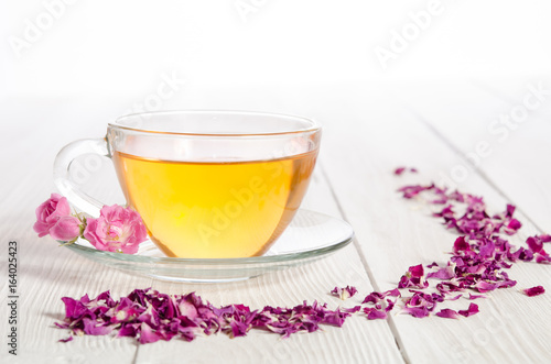 Rose tea and dried petals on white wooden table