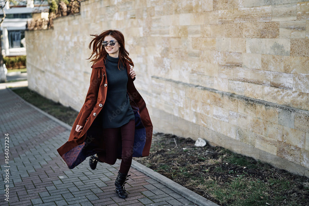 Beautiful young woman in sunglasses running around the city