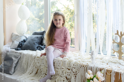 Happy child girl playing and having fun at home near the window