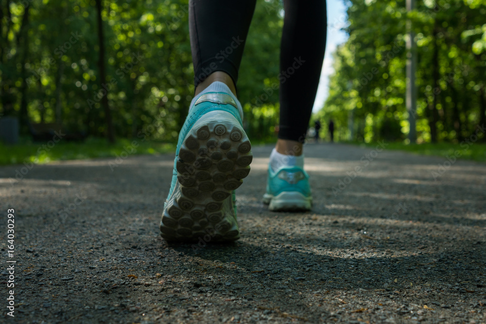 Close up shoe of runner feet running on road at public park.Woman fitness jog workout wellness concept. Close up shoe of runner feet running on road at public park.Woman fitness jog workout wellness concept.