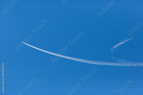 two splitting white jet trails in blue sky