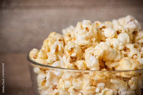 Popcorn in bowl on the wooden table, selective focus