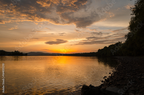 summer sunset on beach by river. cloudy beauty sunset in summer © pellephoto