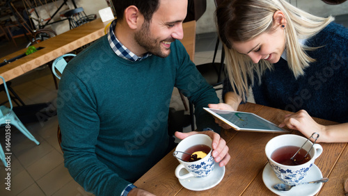 Young attractive man and beautiful woman on date looking on tablet
