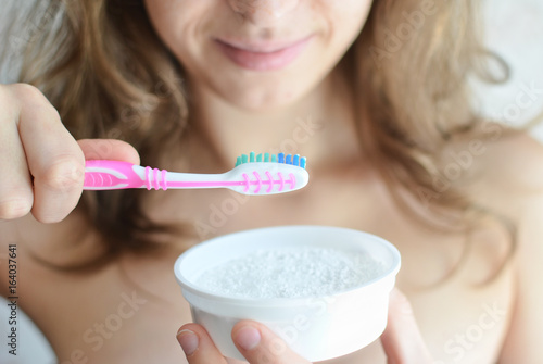 Photos Young pretty girl brushing her tooth with a toothbrush with tooth powder