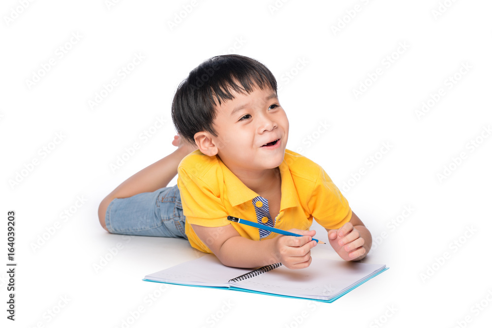 Schoolboy lying down and writing in notebook.