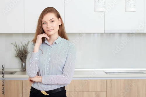 Young beautuful housewife at kitchen. Pretty woman standing in modern kitchen