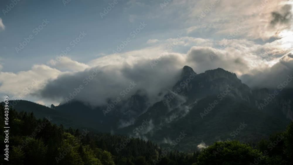 4k timelapse of dynamic cloudy sky with Ceahlau Mountains in the background and shinny green trees in the foreground. Romania. 4k timelapse of dynamic cloudy sky with Ceahlau Mountains in the background and shinny green trees in the foreground. Romania.