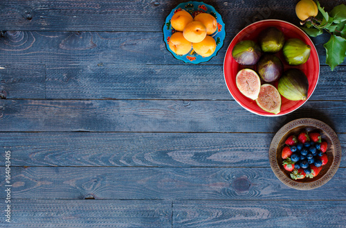 Fresh figs with peaches, apricots, blueberries, strawberries, on a wooden background.