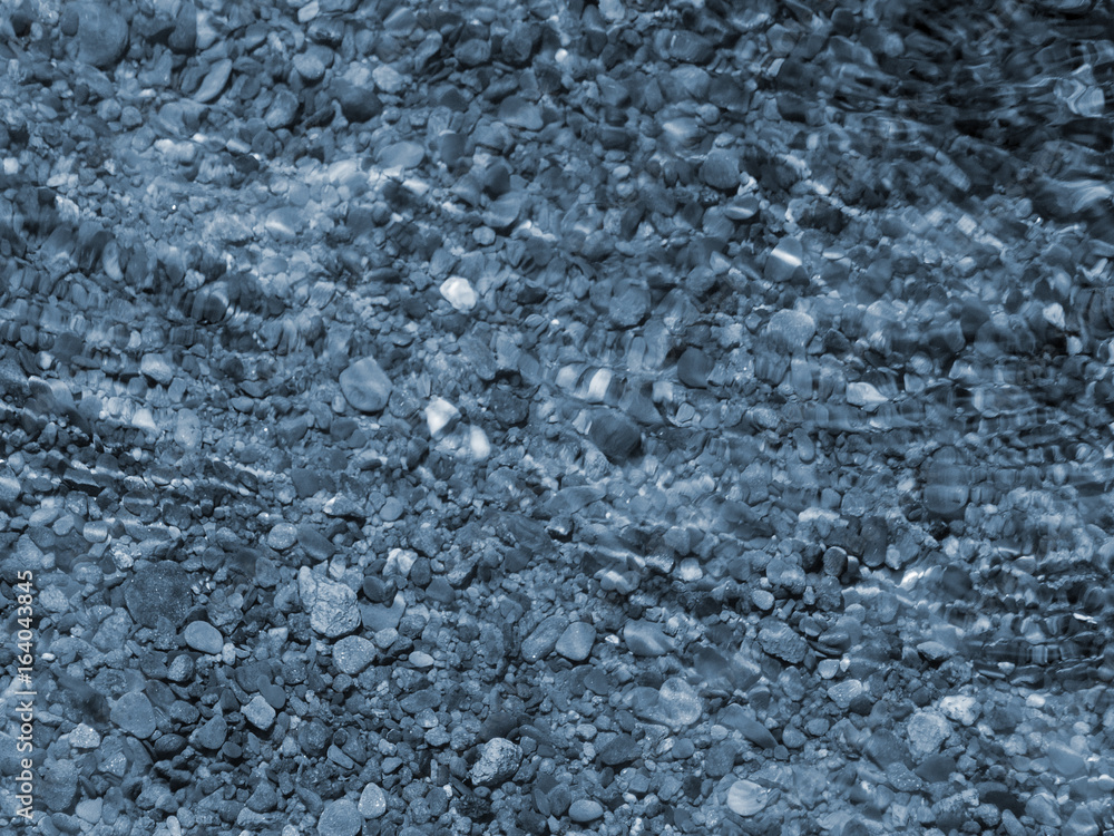 blue pebbles and ripples on water with reflections of light blue pebbles and ripples on water with reflections of light