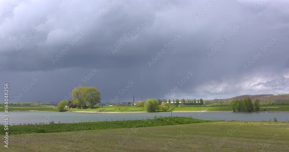 Dark sky above Dutch lowland. River landscape Lower Rhine near Renkum, The Netherlands. Moraine hill in background. Dark sky above Dutch lowland. River landscape Lower Rhine near Renkum, The Netherlands. Moraine hill in background.