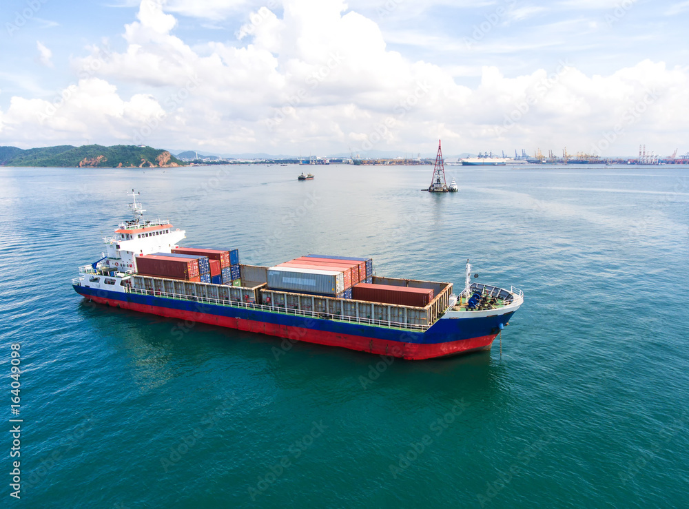 container ship in import export and business logistic.By crane , Trade Port , Shipping.Tugboat assisting cargo to harbor.Aerial view. container ship in import export and business logistic.By crane , Trade Port , Shipping.Tugboat assisting cargo to harbor.Aerial view.