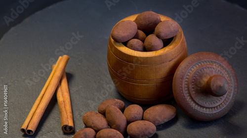 Almonds in black truffles. Chocolate truffle candies with peanuts inside and cinnamon sticks photo
