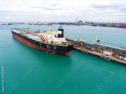 container ship in import export and business logistic.By crane , Trade Port , Shipping.Tugboat assisting cargo to harbor.Aerial view.