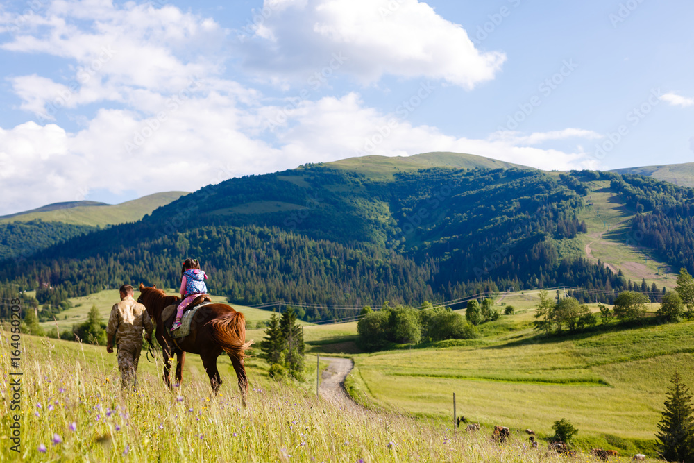 Obraz premium Lovely equestrian - little girl is riding a horse, mountain in the background