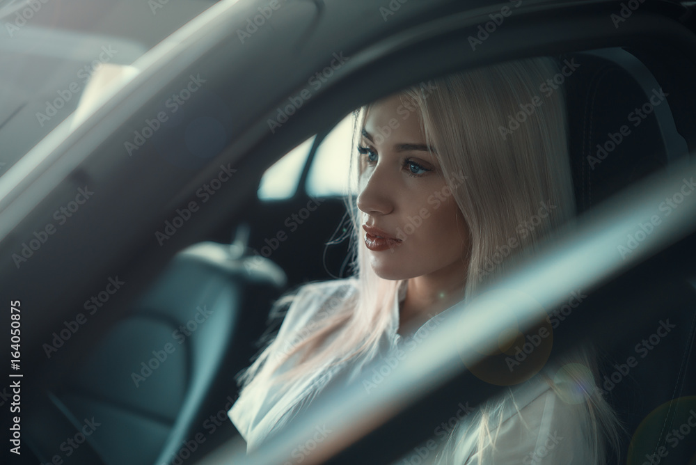 Blonde in the car/ Luxurious girl in a luxury car while driving, close-up.