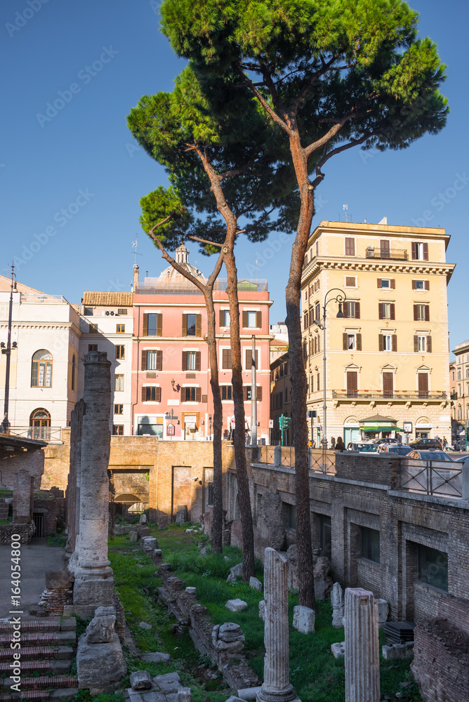 Ancient column ruins surrounded by modern streets in Rome, Italy