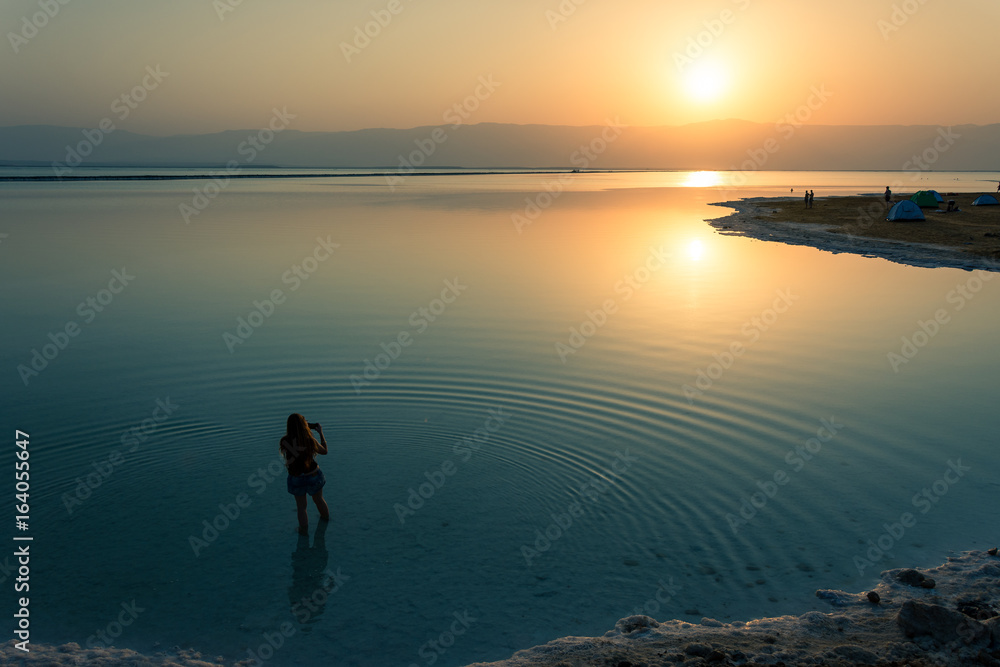 Scenic View Of  a Woman Standing In Sea During Sunrise