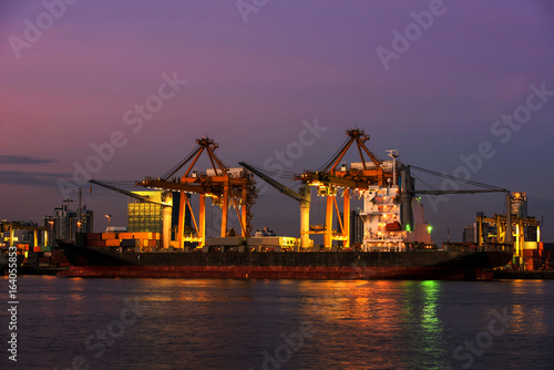 container ship in import export and business logistic.By crane , Trade Port , Shipping.Tugboat assisting cargo to harbor.Aerial view. Top view.