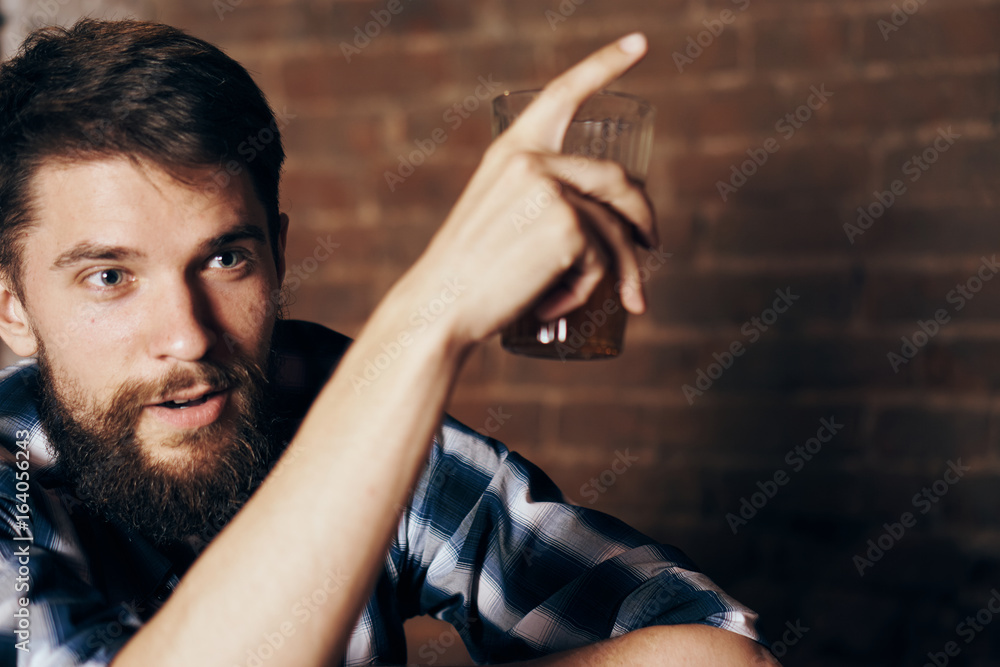 A young guy with a beard drinks beer at the bar