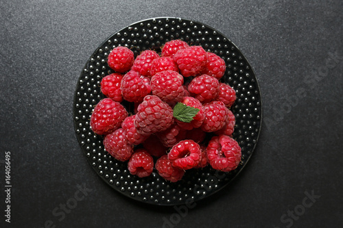juicy raspberries on a black plate