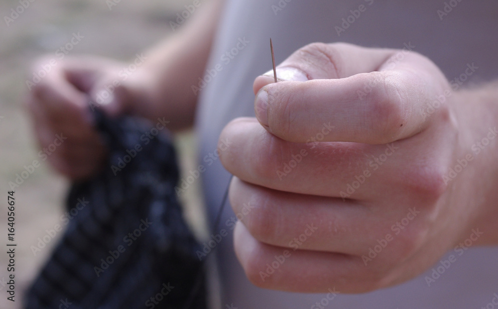 Obraz premium Needle with thread in the man's hand