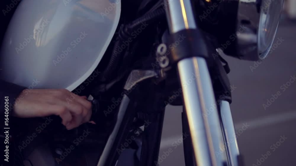 Pretty female biker in shorts starting her motorcycle. Close up of young sexy curly woman in sunglasses on the chopper Pretty female biker in shorts starting her motorcycle. Close up of young sexy curly woman in sunglasses on the chopper