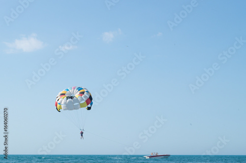 Parasailing is above the sea. Focus on a parachute. Space for text.