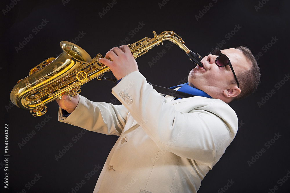 Fototapeta premium Saxophonist playing saxophone. The soloist, saxophonist plays the saxophone. Dressed in a suit. Man.