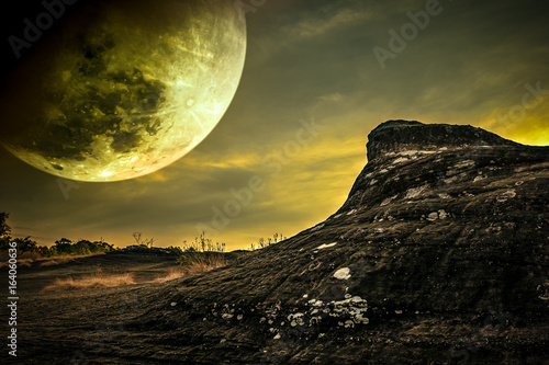 Landscape of rock against sky and full moon above wilderness area in forest.