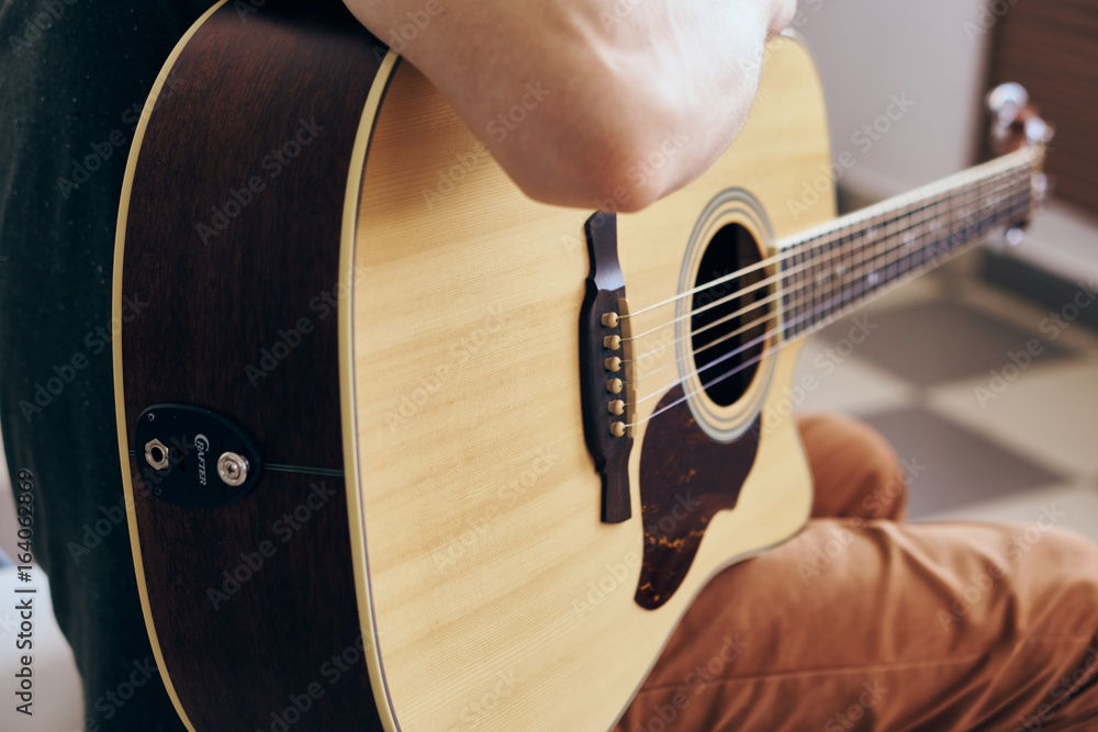 Fototapeta premium Young guy with a beard on a light background playing the guitar