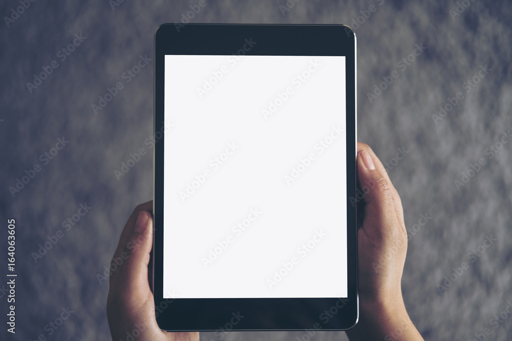 Mockup image of a woman sitting and holding black tablet pc with blank white screen with gray rug in background Mockup image of a woman sitting and holding black tablet pc with blank white screen with gray rug in background