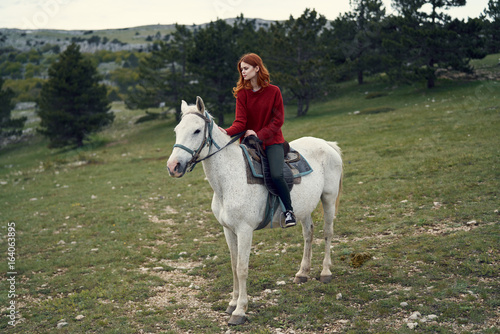 Beautiful young woman walking in the mountains with her horse