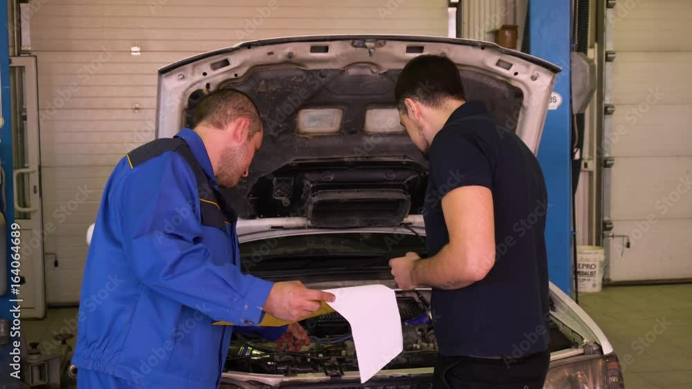 Auto mechanic tells the owner of the car about the detected problems. Auto mechanic tells the owner of the car about the detected problems.